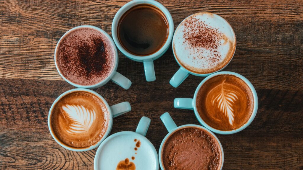 7 cups of coffee in a circle with coffee art on top