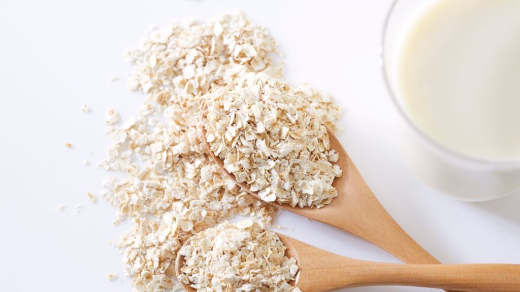 Wooden spoon with oates and a glass of milk